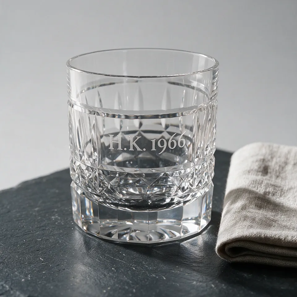 Leeres Kristallglas auf Schiefer mit dem gravierten Monogramm „H.K. 1966“